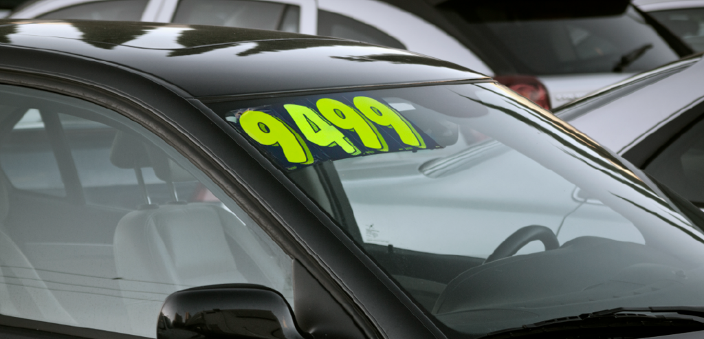 自動車ディーラーのイメージ画像。車のフロントガラスに値段が貼ってある。